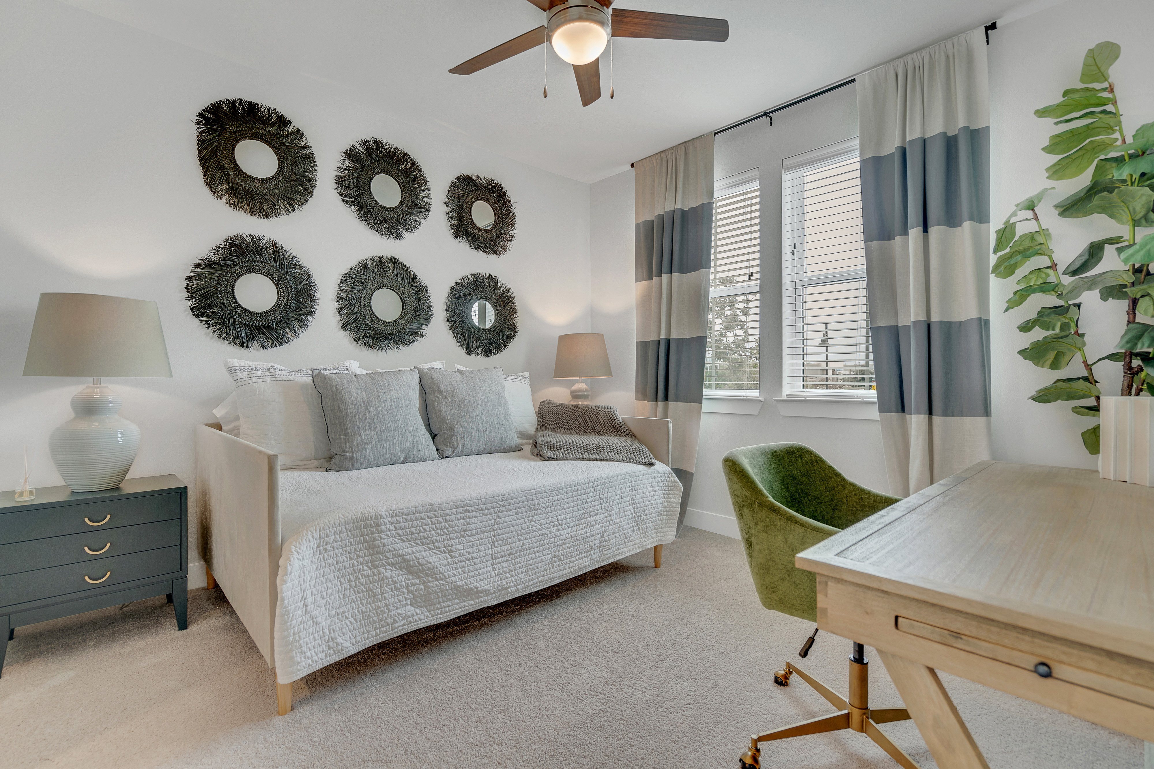 a bedroom with a daybed, desk, and ceiling fan at a senior apartment community